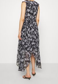 Black floral maxi dress with a high-low hem, sheer fabric, and ruffled sleeves. Features a fitted waist and delicate white flower patterns.