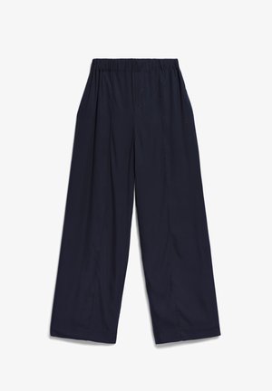 Donkerblauwe wijde broek met een elastische tailleband, voorzien van zijzakken en een zachte textuur. Subtiele branding aan de zijkant.
