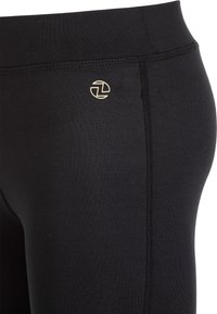 Sorte leggings lavet af strækbart stof har et guld logo på hoften og flade sømme langs siderne for komfort og et strømlinet udseende.