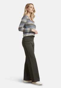 Knitted sweater with a zigzag pattern in blue, gray, and cream; paired with high-waisted dark gray wide-leg pants and white sneakers.