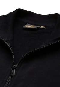 Giacca nera con zip e colletto e polsini a coste. Presenta una texture liscia e un dettaglio con zip in metallo. Etichetta interna visibile.