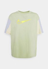 Světle zelené tričko s krátkým rukávem s fialovými a béžovými detaily, na přední straně je vyšité žluté logo Nike swoosh. Bavlněná tkanina.
