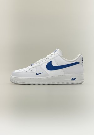 Άσπρο αθλητικό παπούτσι Nike Air Force 1 με μπλε λογότυπα swoosh και κείμενο "AIR" στη σόλα, εμφανίζεται από το πλάι σε ουδέτερο φόντο.