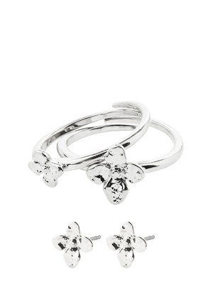 Anneaux ouverts de couleur argentée et boucles d'oreilles clous assorties, chacun présentant un petit motif floral texturé.
