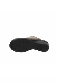 Suola della scarpa in gomma nera testurizzata con scanalature sottili, attaccata a una tomaia beige, caratterizzata da una forma arrotondata. Gli accenti includono dettagli di cucitura.