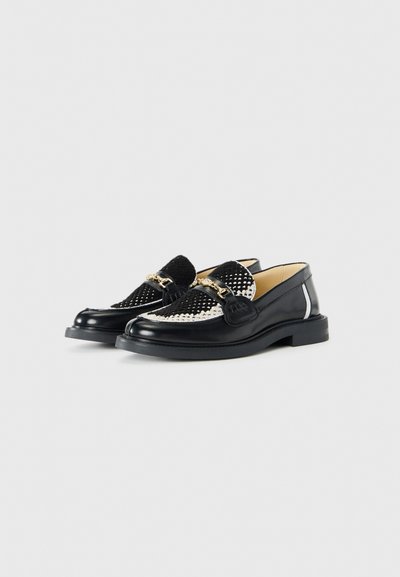 Black leather loafers with a woven black and white textile front, featuring a gold-toned chain accent and a rounded toe.