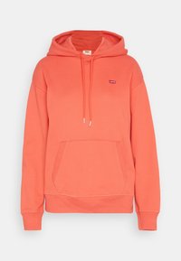 Coral hoodie made of soft fabric, featuring a front pocket, drawstring hood, and a small logo tag on the chest. Ribbed cuffs and hem.