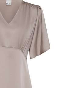 Robe beige clair à col en V avec manches courtes volantées et plis subtils près de l'épaule, dotée d'une taille cintrée.