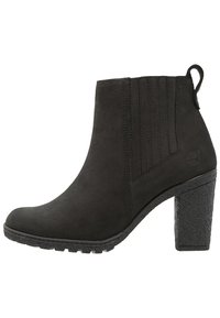 La botte courte en suède noir présente un bout arrondi, des panneaux latéraux en élasthanne et un talon bloc noir texturé pour la stabilité et le confort.