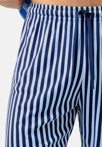 Donkerblauw en lichtblauw gestreepte broek met een elastische tailleband, trekkoord en een gladde textuur, met een consistent verticaal patroon.