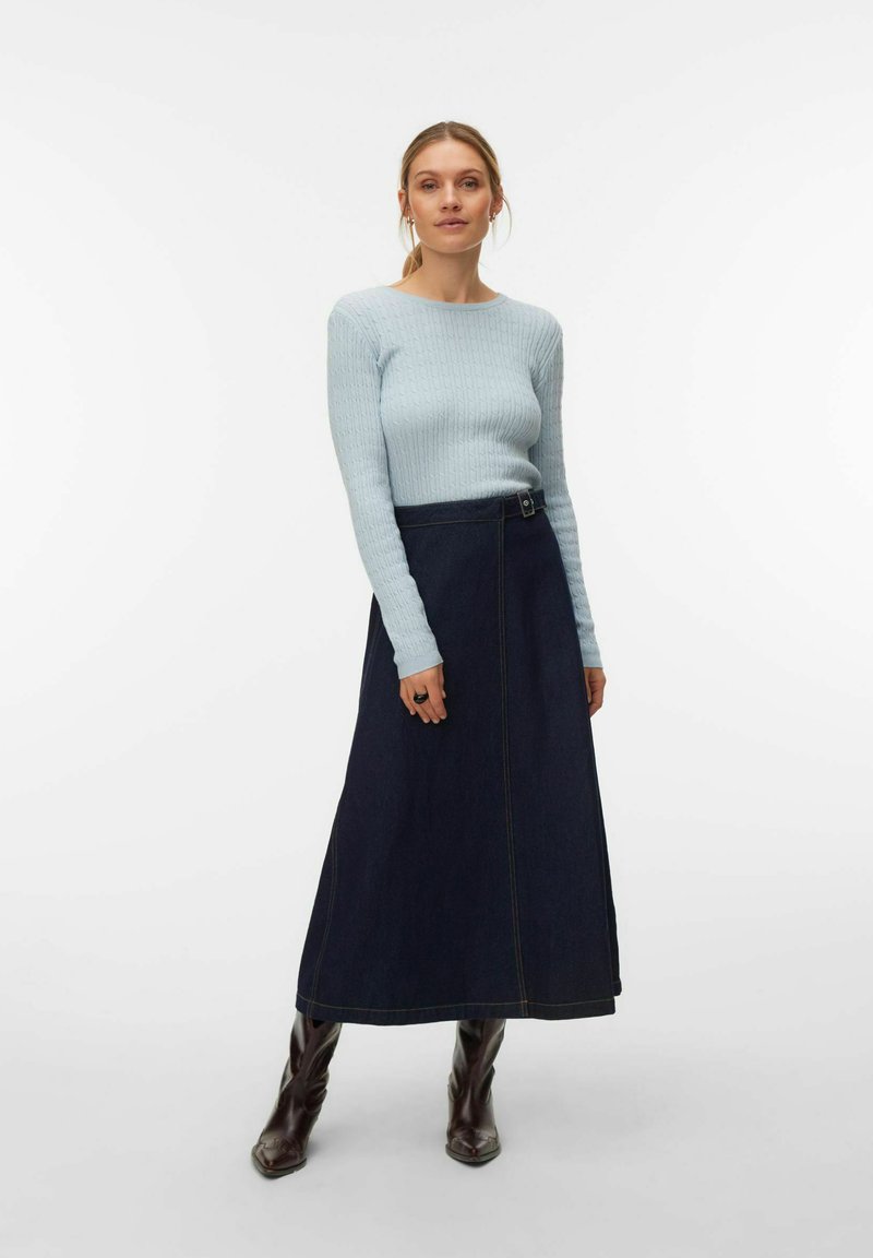 Pull côtelé bleu clair, jupe longue en denim foncé avec bouton décentré, associée à des bottines marron ajustées. Design épuré et minimaliste.
