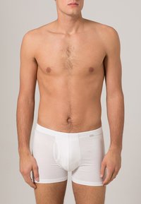 Vita bomullsboxer med en åtsittande design, elastisk midjeband och knappgylf. Slät textur, inga synliga mönster eller logotyper.