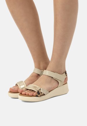 Sandalias de cuña beige con correas texturizadas, que presentan una combinación de acabados lisos y en relieve, además de un sutil detalle de estampado animal en la puntera.