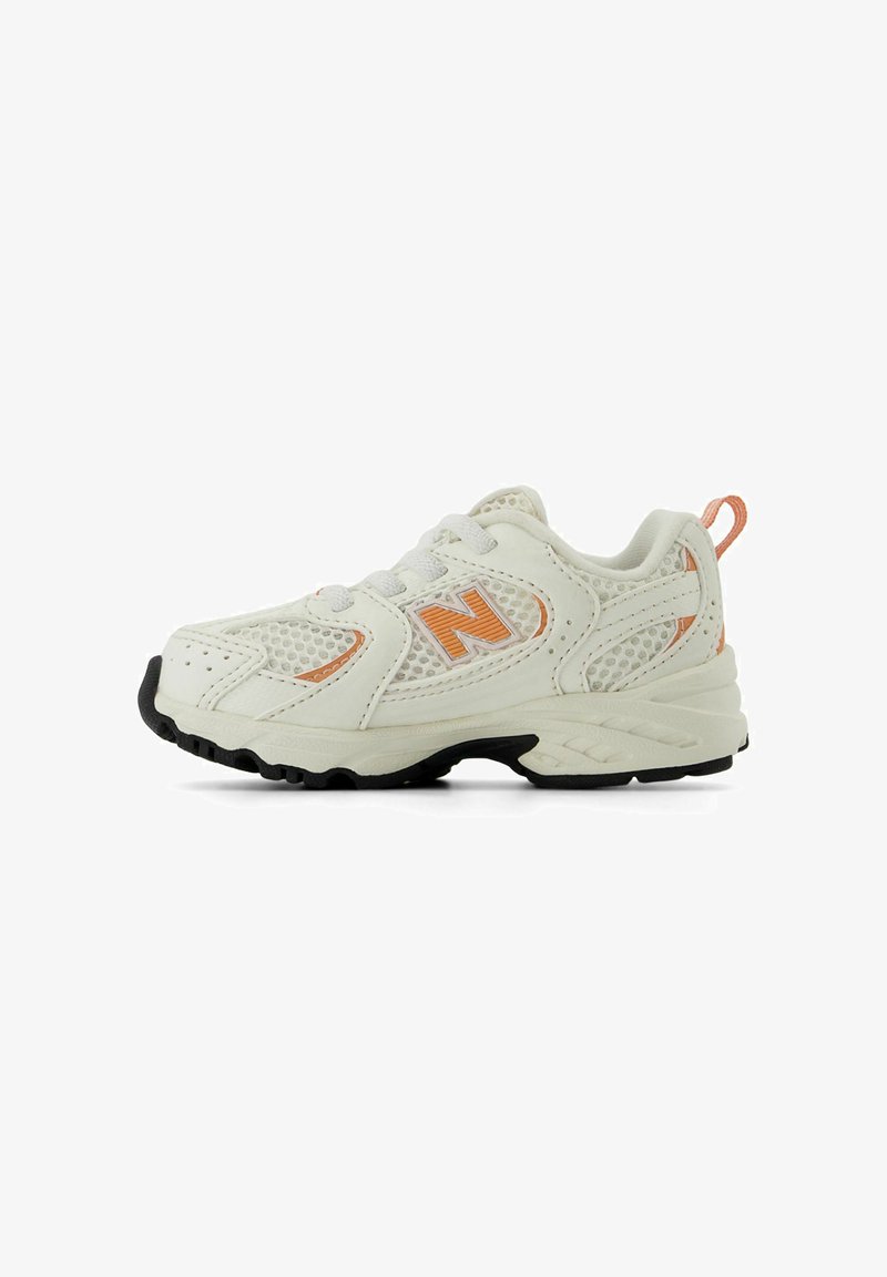 White athletic shoe with orange accents, mesh panels, and a textured rubber sole. Features laces and a rear pull tab for easy wear.
