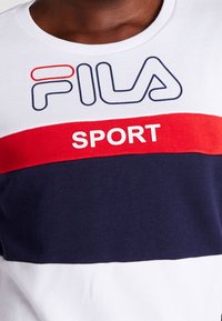 Bílý, červený a námořnický pruhovaný bavlněný tričko s logem "FILA" v modré barvě a "SPORT" v červené, s žebrovaným kulatým výstřihem.