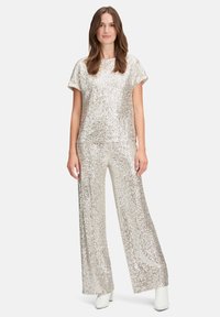 Glanzend zilveren twee-delig outfit met een losse korte mouwen top en wijde broek, gemaakt van paillettenmateriaal met een gladde textuur.