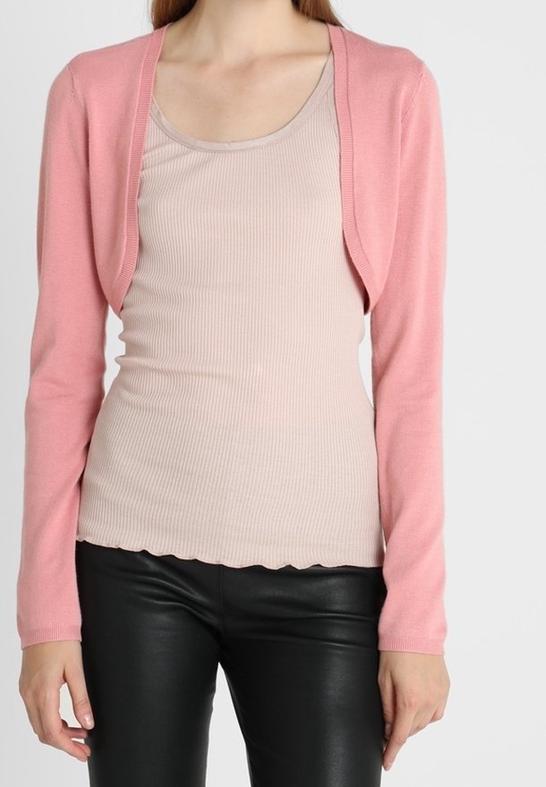 Cardigan rosa chiaro a maniche lunghe, in morbido tessuto a maglia con design a apertura frontale, abbinato a un top aderente beige a coste e pantaloni neri.