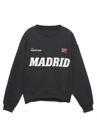 Čierna mikina s okrúhlym výstrihom, zdobená odvážnym bielym textom "MADRID", s ružovými akcentmi a grafickými detailmi. Mäkká tkanina, voľný strih.
