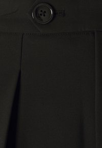 Černá látková sukně s hladkým povrchem, která se vyznačuje výrazným zapínáním na knoflík a sklady pro přidaný designový detail.