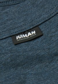 Tmavě modré bavlněné tričko s texturovaným povrchem. Obsahuje černou visačku s nápisem "IUMAN" bílým písmem a pod ním "intimissimi uomo".