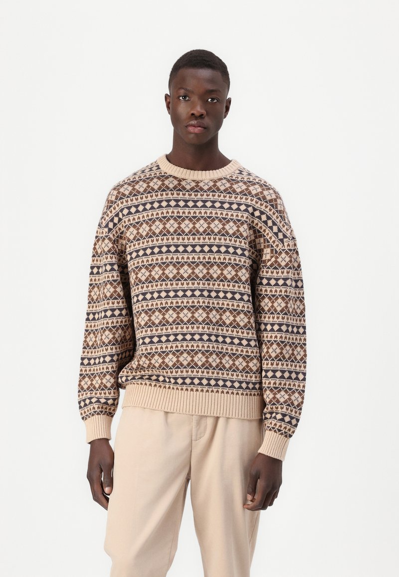 Strikket sweater i beige med et geometrisk mønster i brune og marine nuancer. Ribbede halsudskæring og manchetter, løs pasform, tekstureret stof.