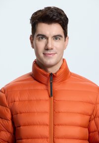 Polstret orange jakke med høj krave og frontlynlås. Har quiltet struktur og sort lynlåsdetalje for kontrast.
