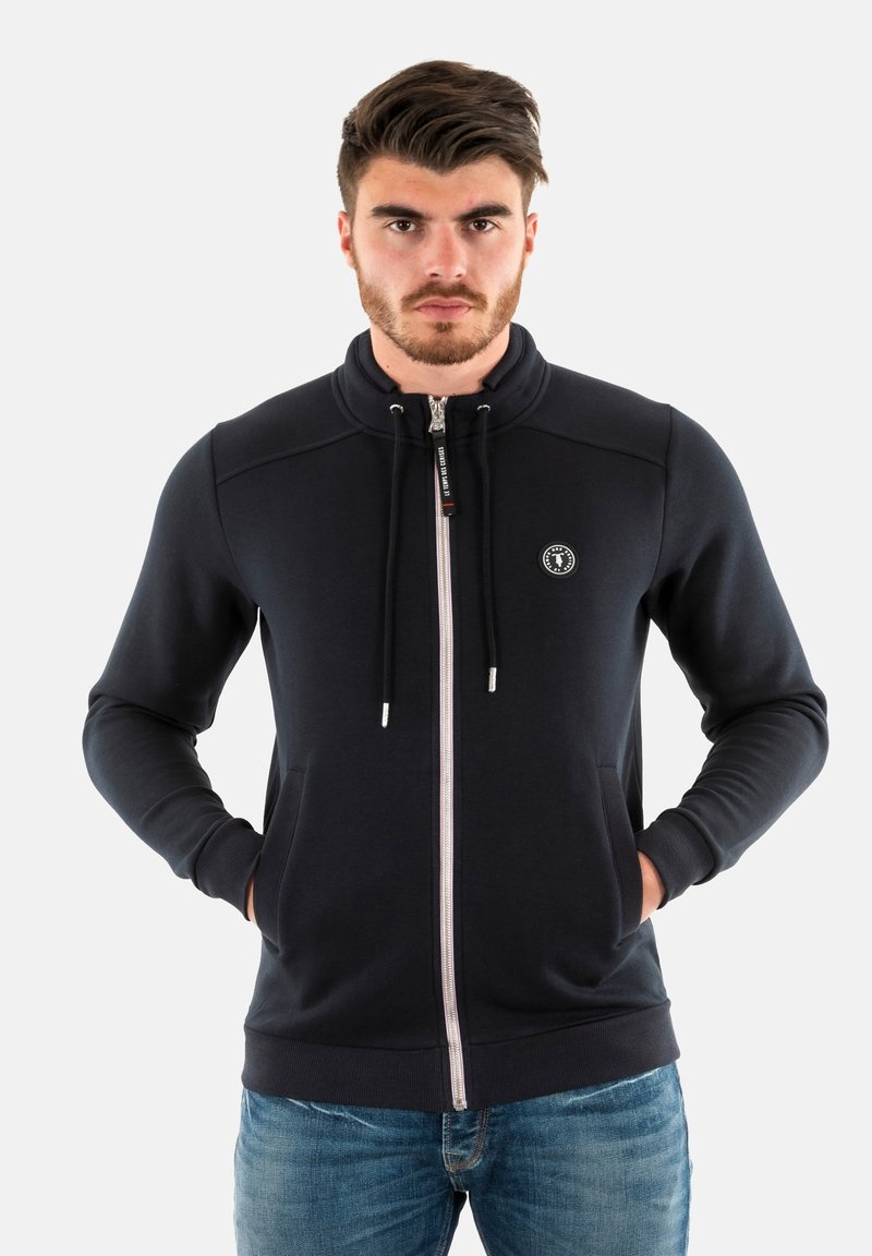 Donker marineblauwe rits-hoodie van zacht materiaal, met een hoge kraag, twee voorzakken en trekkoorden met zilverkleurige accenten.