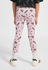 Różowe legginsy z powtarzającym się czarnym wzorem logo, z dopasowanym krojem i elastyczną talią. W zestawie z białymi skarpetkami i trampkami.