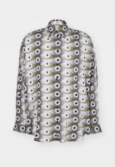 Chemise à manches longues en tissu léger, arborant un motif répétitif d'yeux dans des tons de vert et de gris, avec des accents et des boutons noirs.