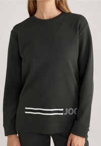 Tmavě zelená mikina s dlouhými rukávy, kulatým výstřihem a bílým proužkem na lemu, s nápisem "JOOG" na přední straně.