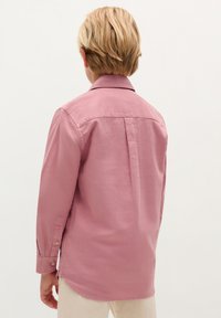 Langærmet skjorte i blødt, lys pink stof. Har klassisk krave, knapmanchetter og en let buet søm. Enkel, ren design.