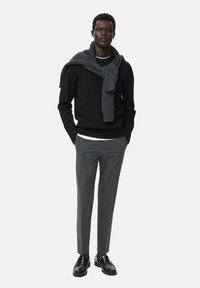 Zwarte trui, grijze sjaal, witte shirt en grijze slim-fit broek. Zwarte leren schoenen. Slim-fit silhouet met gestructureerd sjaaldetail.