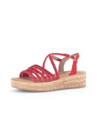 Red strappy sandals featuring glittery straps, a tan footbed, and a cork-like textured wedge sole with layered detailing. Buckle closure at the ankle.