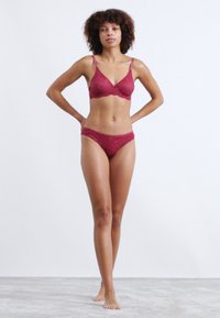 Set di bra in pizzo bordeaux e bikini coordinato, con spalline regolabili, motivo floreale e texture liscia.