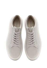 Baskets en cuir blanc avec un bout arrondi, une texture lisse, des lacets plats et un design minimaliste. Comprend une languette rembourrée et des accents en daim.