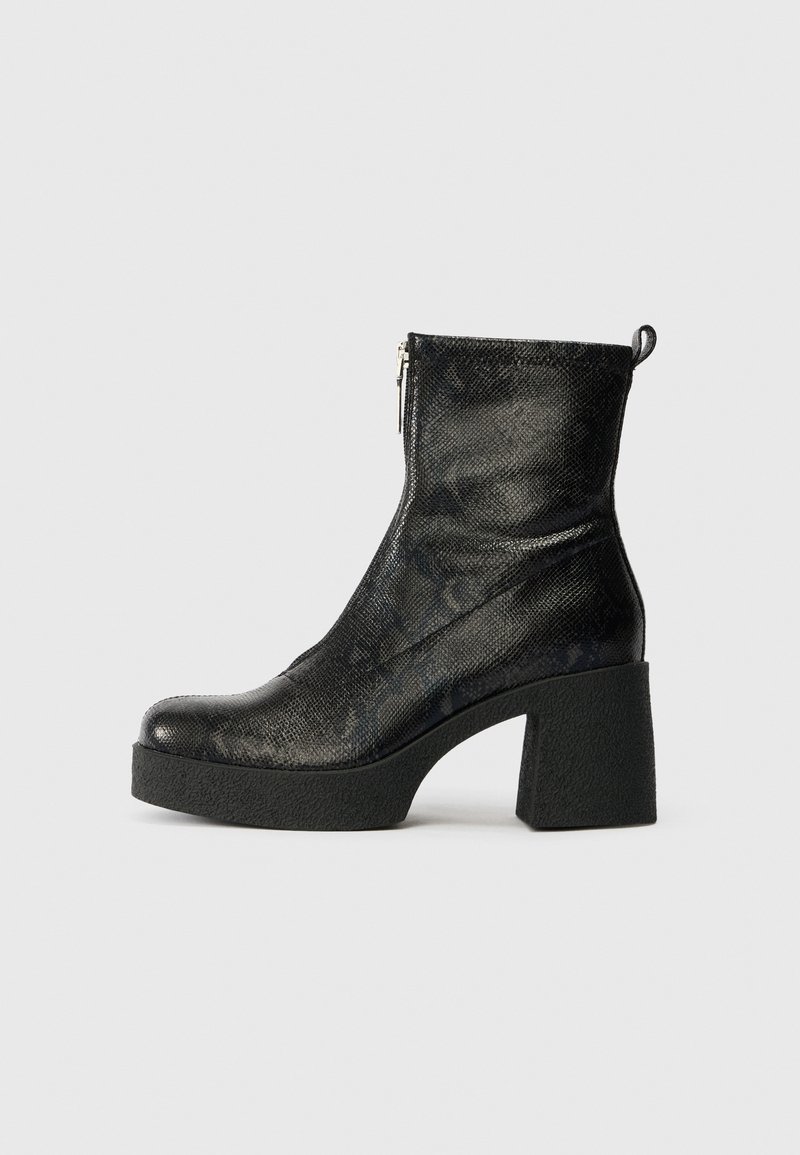 Botte cheville en cuir noir texturé avec fermeture éclair latérale, semelle plateforme et talon haut épais, présentée de profil sur un fond uni.