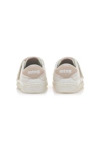 Zapatillas blancas con un acabado de cuero suave, forma redondeada y un suave acento beige en el talón. Presentan una correa de velcro y un logo.