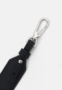 Llavero de cuero negro con un clip metálico plateado. Presenta un borde cosido y un pequeño remache decorativo. Se aprecia el detalle de la superficie texturizada.