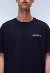 Navy cotton t-shirt with a round neckline. Features a small chest logo in white reading "Napapijri geographic." Short sleeves, relaxed fit.