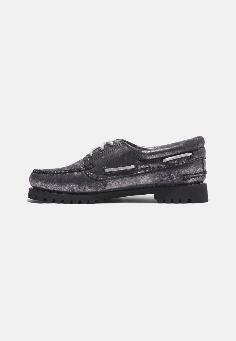 Scarpe da barca testurizzate in nero e grigio con lacci, caratterizzate da una punta arrotondata, cuciture visibili e una suola in gomma flessibile.