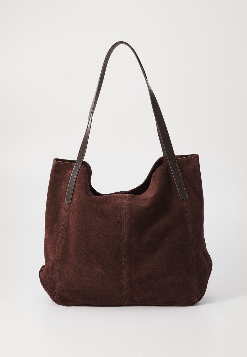 Sac fourre-tout en daim marron avec deux bretelles en cuir marron foncé sur un fond clair uni.