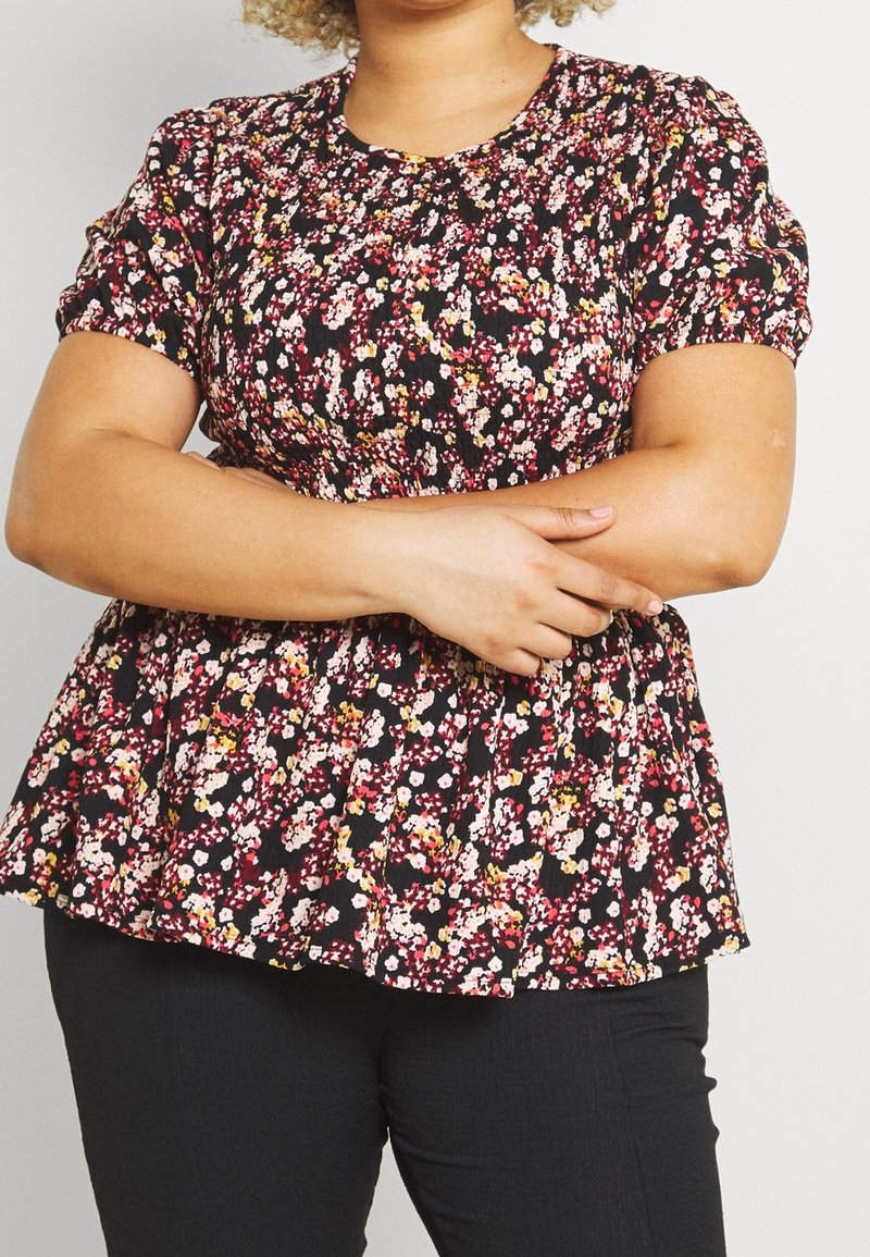 Schwarzes, blühendes, kurzärmliges Peplum-Top mit rosa, gelben und weißen Blumen, das an den Schultern geraffte Akzente und einen runden Ausschnitt aufweist.