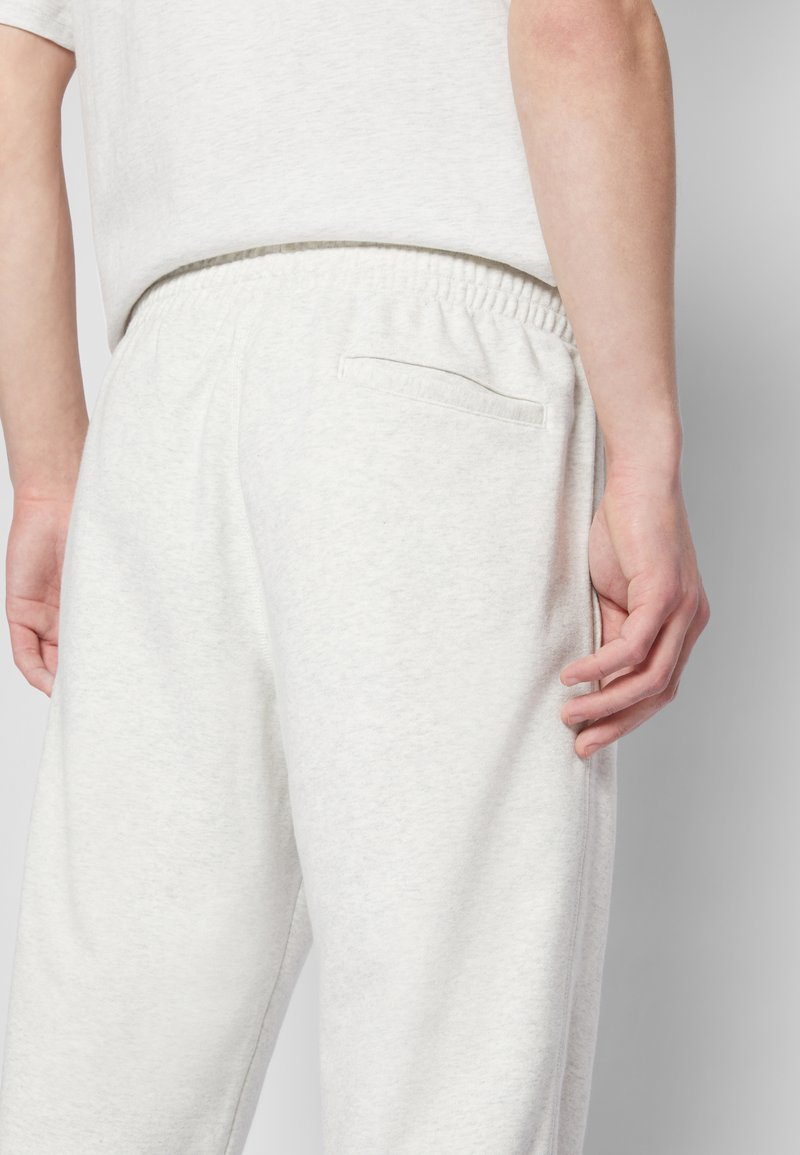 Pantalon de jogging gris clair en tissu doux, avec une taille élastique, une poche arrière et une coupe décontractée. Idéal pour un look casual.