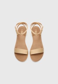 Beige skinnsandaler med to horisontale stropper og ankelspenne. Glatt tekstur og sømmet kanter på en lys brun såle.