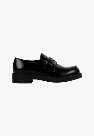 Mocassin en cuir noir brillant avec une semelle épaisse et un détail de bride sur le dessus, vu de côté sur fond blanc.