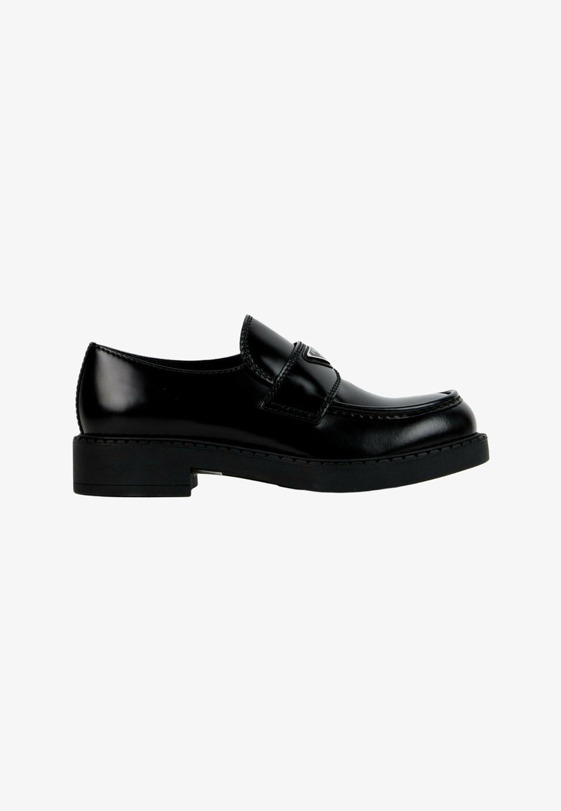 Mocassin en cuir noir brillant avec une semelle épaisse et un détail de bride sur le dessus, vu de côté sur fond blanc.