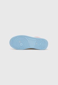 Semelle de chaussure en caoutchouc bleu avec des motifs de crantage circulaires. Texture lisse, forme arrondie et trous de drainage visibles.