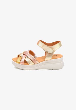 Sandalia de cuña con tiras entrecruzadas en metalizado oro, oro rosa y plata, correa en el tobillo con cierre de velcro y suela blanca y gruesa.