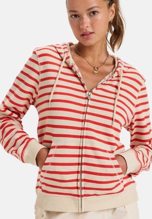 Red and beige striped zip-up hoodie with a front pocket, drawstring hood, and ribbed cuffs. Cotton material with a soft texture.