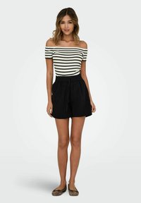 Schulterfreies gestreiftes Oberteil in Weiß und Schwarz, kombiniert mit locker sitzenden schwarzen Shorts mit elastischem Bund und Kordelzug.